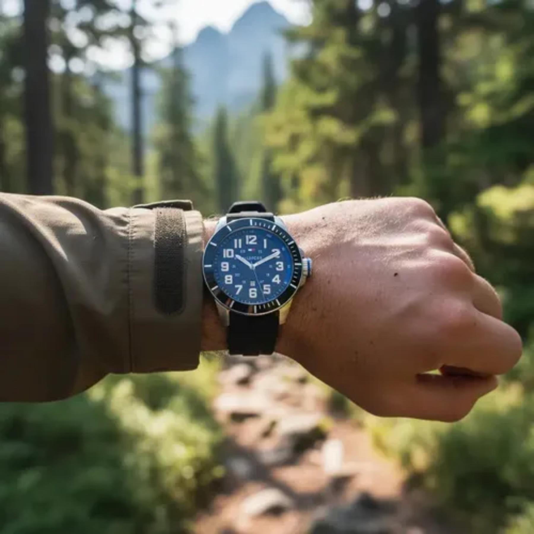 Tommy Hilfiger 179102 men’s sport watch with black dial and black silicone strap worn on the wrist outdoors in a forest setting.