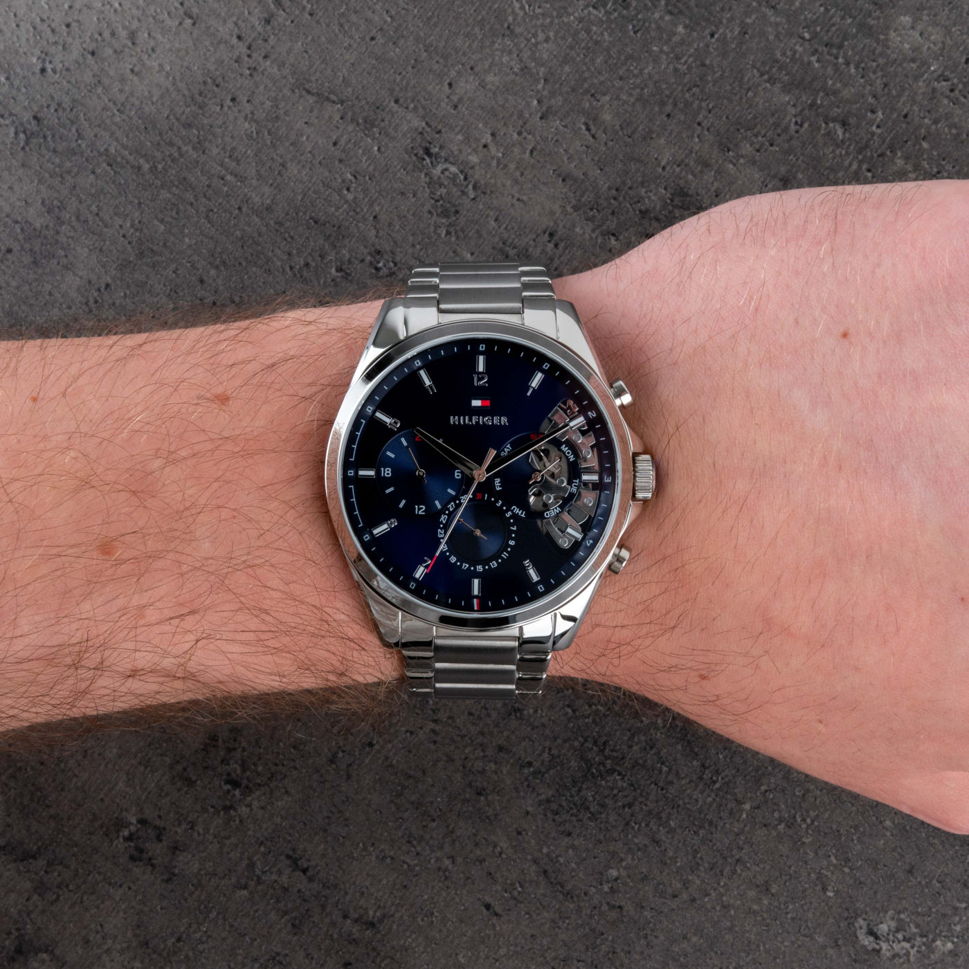 Tommy Hilfiger 1791348 chronograph watch worn on the wrist with blue dial, subdials and stainless steel bracelet.