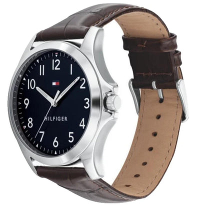 Tommy Hilfiger 1791449 men’s watch with navy blue dial, silver-tone case, and brown crocodile-pattern leather strap shown in an angled side view.