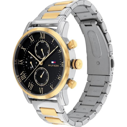 Tommy Hilfiger 1791539 chronograph watch with black dial, subdials, gold-tone bezel and two-tone stainless steel bracelet shown from side angle.