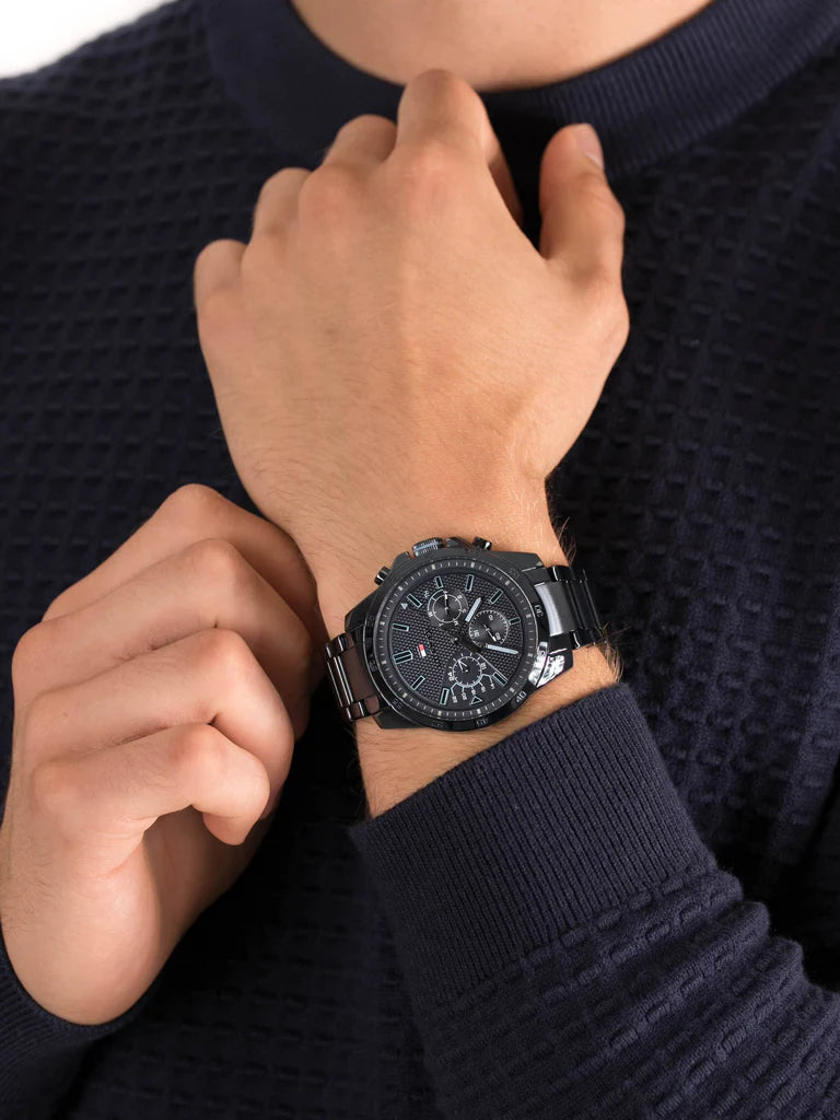 Tommy Hilfiger 1791560 men’s chronograph watch with textured blue dial and blue stainless steel bracelet worn on the wrist with a dark casual outfit.