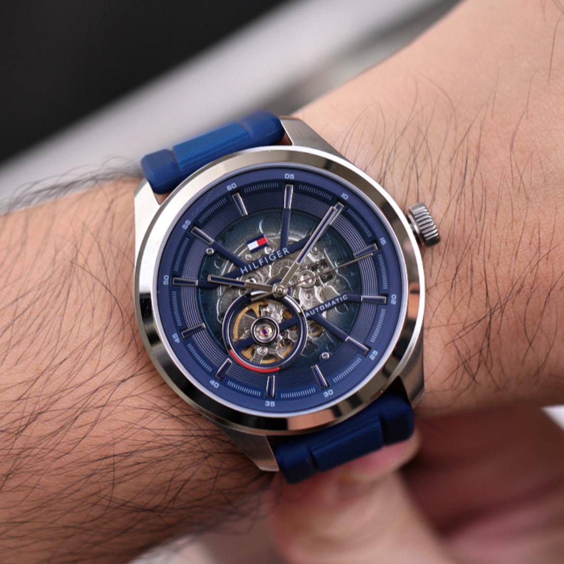 Tommy Hilfiger 1791885 men’s automatic watch with blue skeleton dial and blue silicone strap worn on the wrist.
