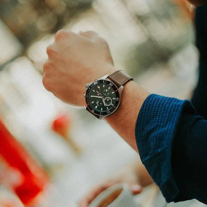 Tommy Hilfiger 1791983 men’s multifunction watch with green dial and brown leather strap worn on the wrist outdoors with a casual outfit.